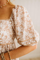 Close-up of a person wearing a floral dress with a neutral background
