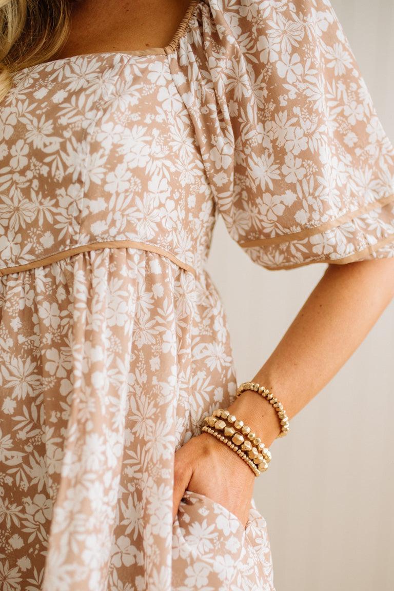 Close-up of a person wearing a floral dress with a neutral background