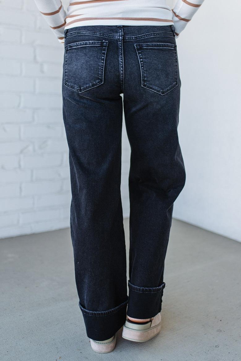Person wearing dark blue jeans with a white brick wall background