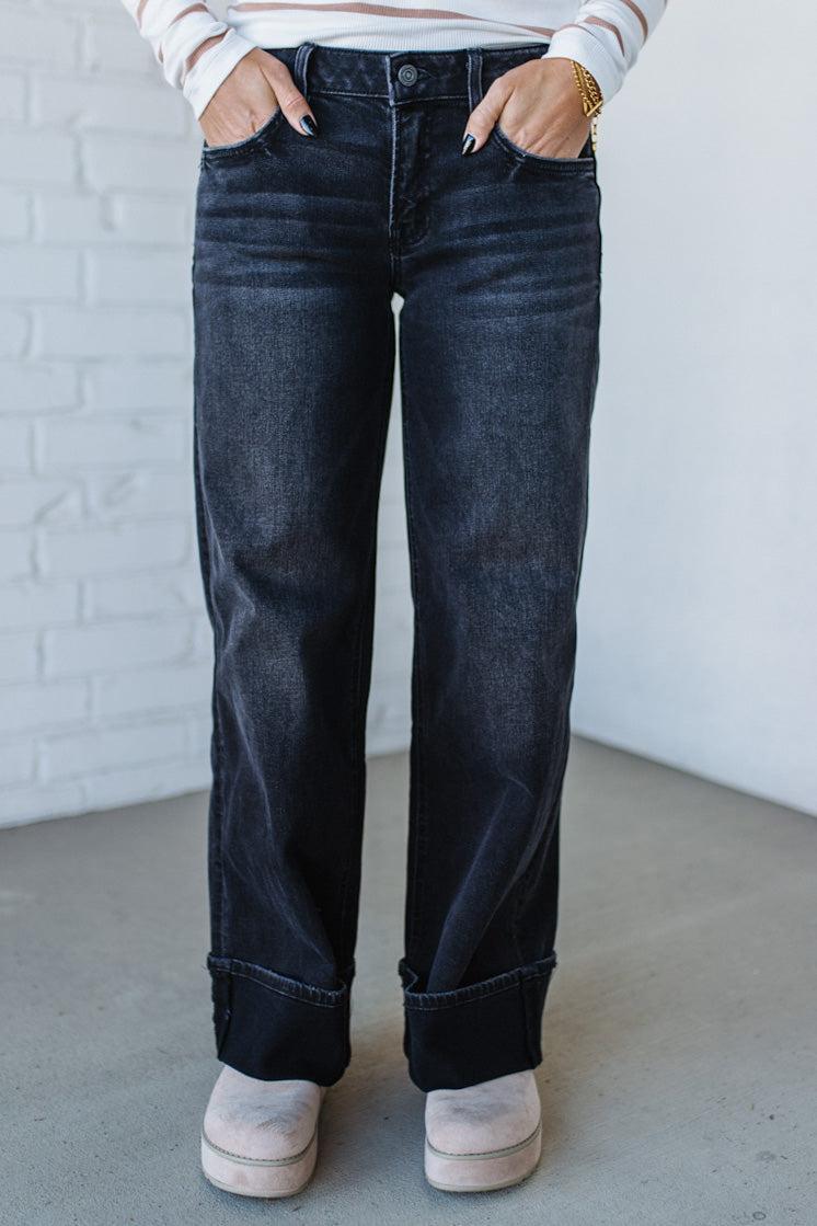 Person wearing dark blue jeans with a white brick wall background
