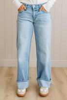 Light blue jeans worn by a person on a wooden floor with a neutral wall background