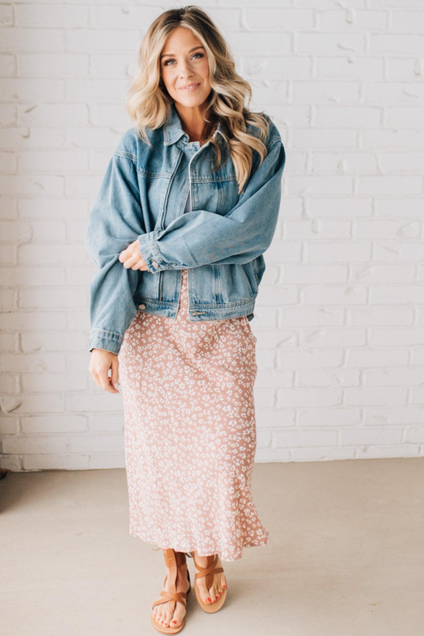 Blonde woman wearing a medium wash zip front denim moto jacket.