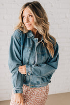 Blonde woman wearing a medium wash zip front denim moto jacket.