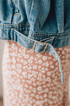 Blonde woman wearing a medium wash zip front denim moto jacket.