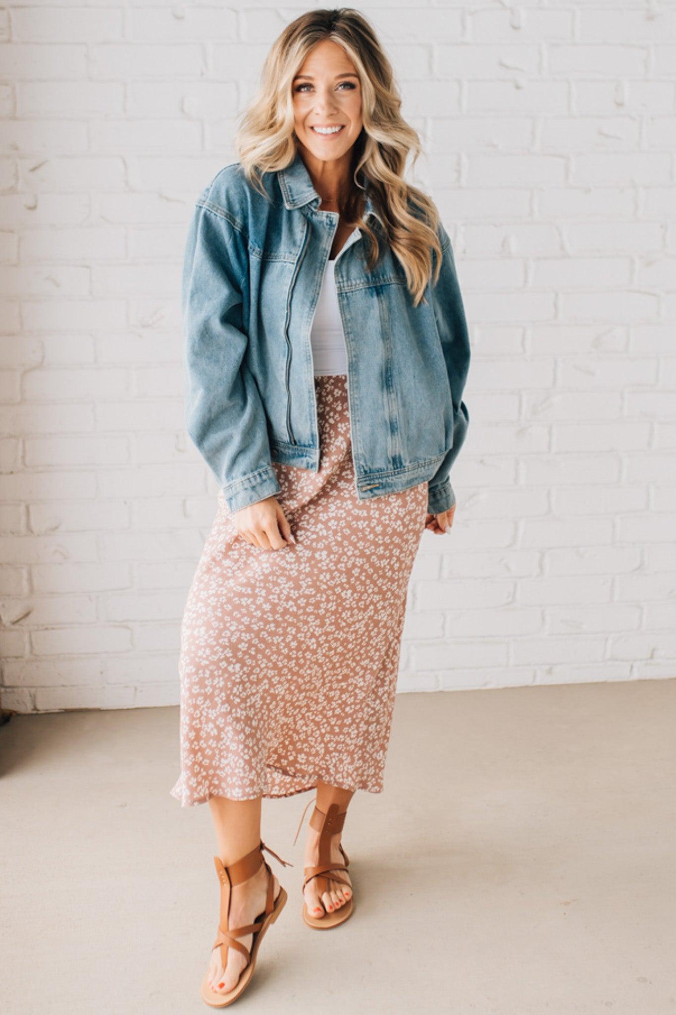 Blonde woman wearing a medium wash zip front denim moto jacket.