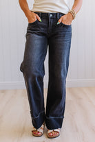 Person wearing dark blue jeans with a plain background