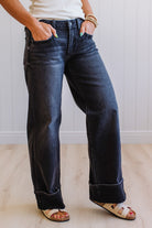 Person wearing dark blue jeans with a plain background
