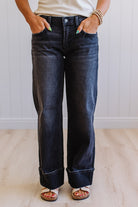Person wearing dark blue jeans with a neutral background