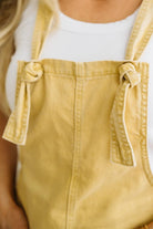 Yellow overalls worn by a person with a white shirt underneath