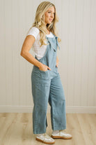 Woman wearing denim overalls against a neutral background
