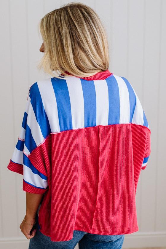 Person wearing a red, white, and blue striped shirt with a red corduroy panel.