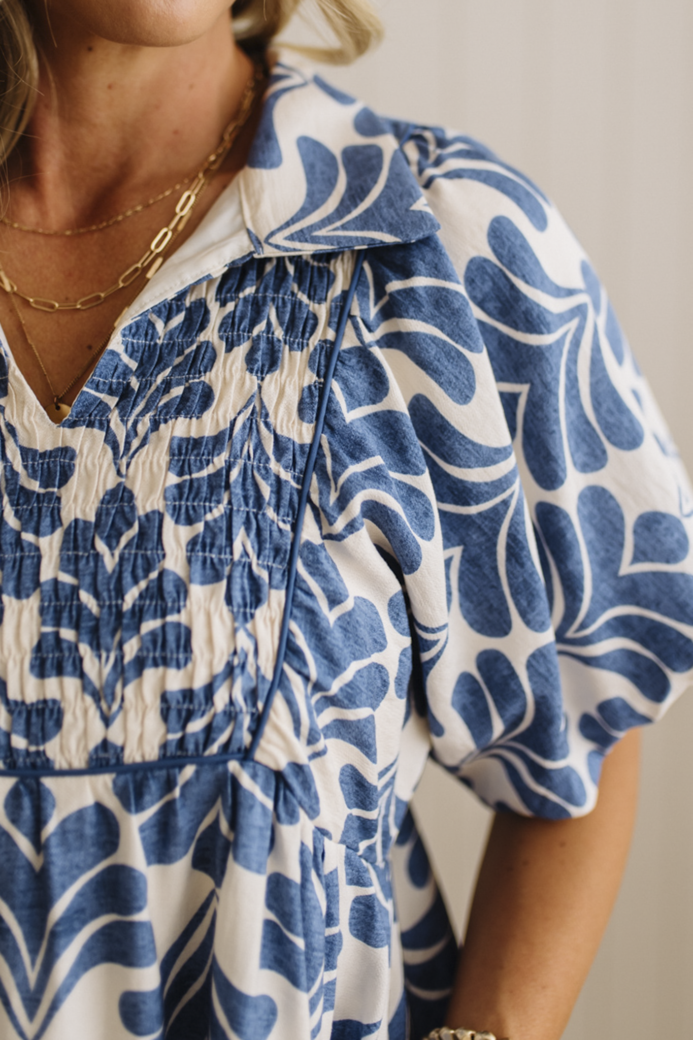 Close-up of a person wearing a blue and white patterned dress with a neutral background