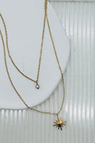 Two gold necklaces with star and heart pendants on a white surface.