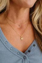 Close-up of a person wearing a gold necklace with a star pendant.