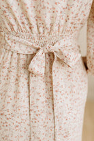 Floral patterned dress with a tie waist on a plain background