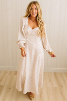 Woman wearing a white floral dress with long sleeves in a room with wooden flooring.