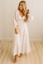 Woman wearing a white lace dress in a room with wooden flooring and a white wall.