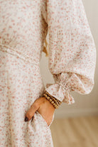Close-up of a person wearing a floral dress with puffed sleeves, holding their hand in front.