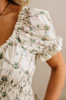 Close-up of a floral dress with ruffled details on a neutral background