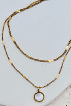 Two gold necklaces on a white surface