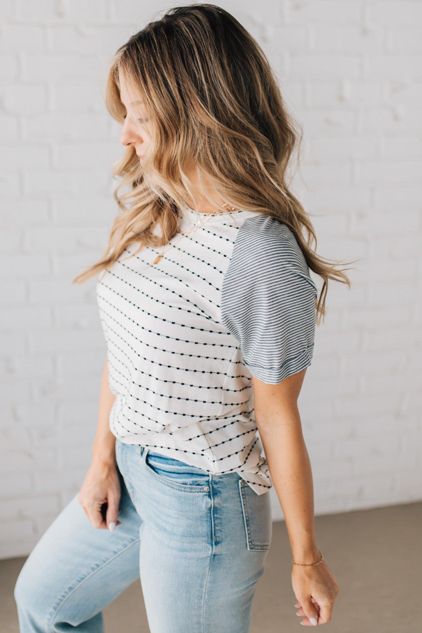 BLONDE WOMAN WEARING A ROUND NECK TOP WITH MICRO STRIPED RAGLAN SHORT SLEEVES, AND DOTTED STRIPE KNIT BODY.