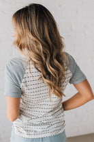 BLONDE WOMAN WEARING A ROUND NECK TOP WITH MICRO STRIPED RAGLAN SHORT SLEEVES, AND DOTTED STRIPE KNIT BODY.