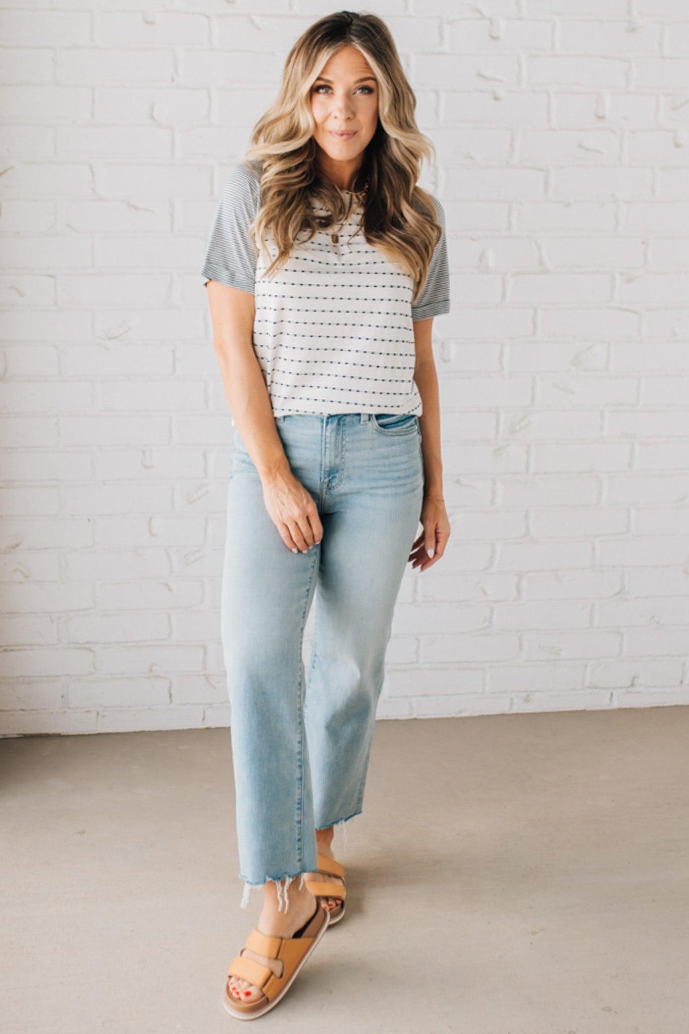 BLONDE WOMAN WEARING A ROUND NECK TOP WITH MICRO STRIPED RAGLAN SHORT SLEEVES, AND DOTTED STRIPE KNIT BODY.