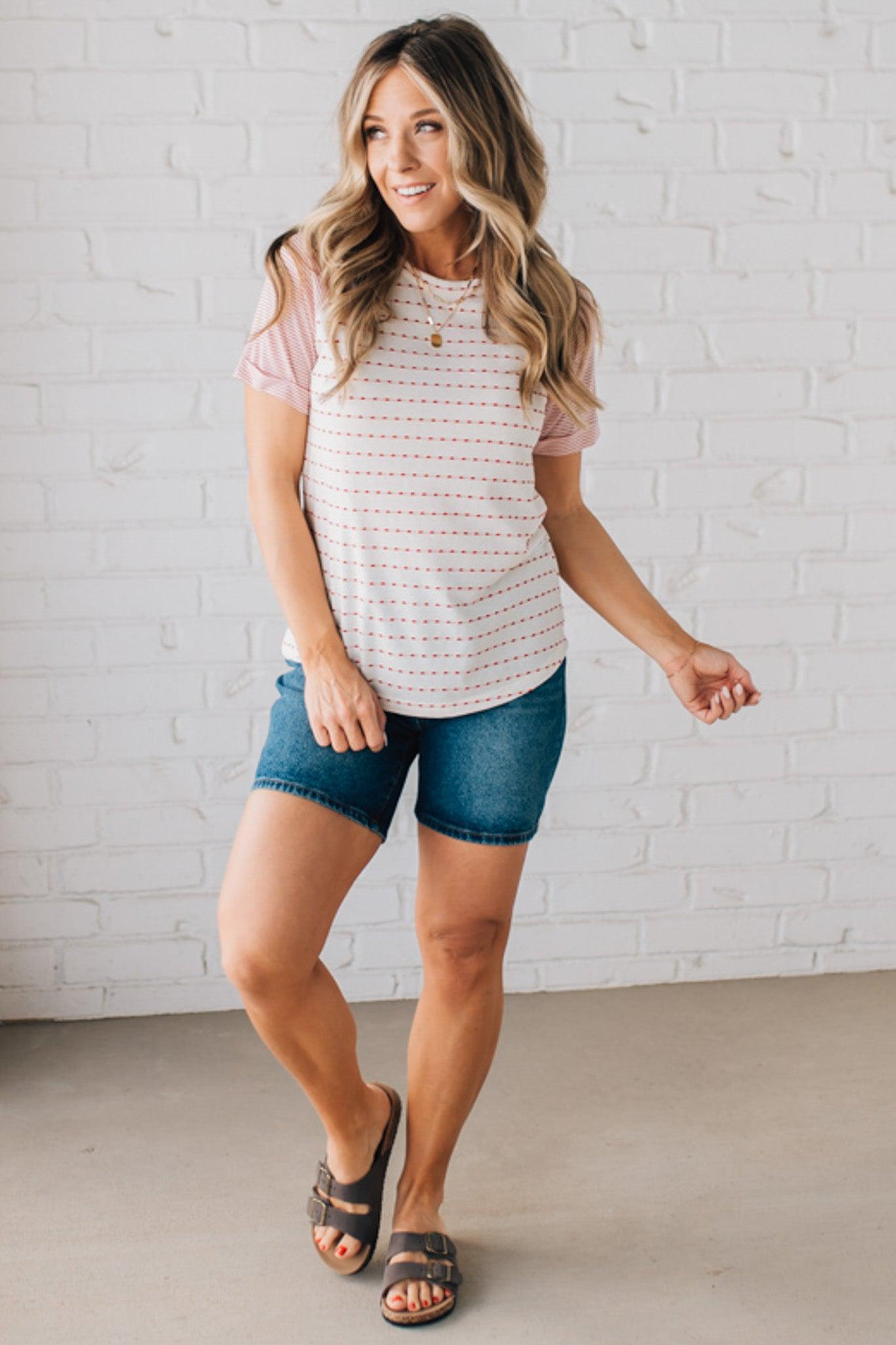 BLONDE WOMAN WEARING A ROUND NECK TOP WITH MICRO STRIPED RAGLAN SHORT SLEEVES, AND DOTTED STRIPE KNIT BODY.