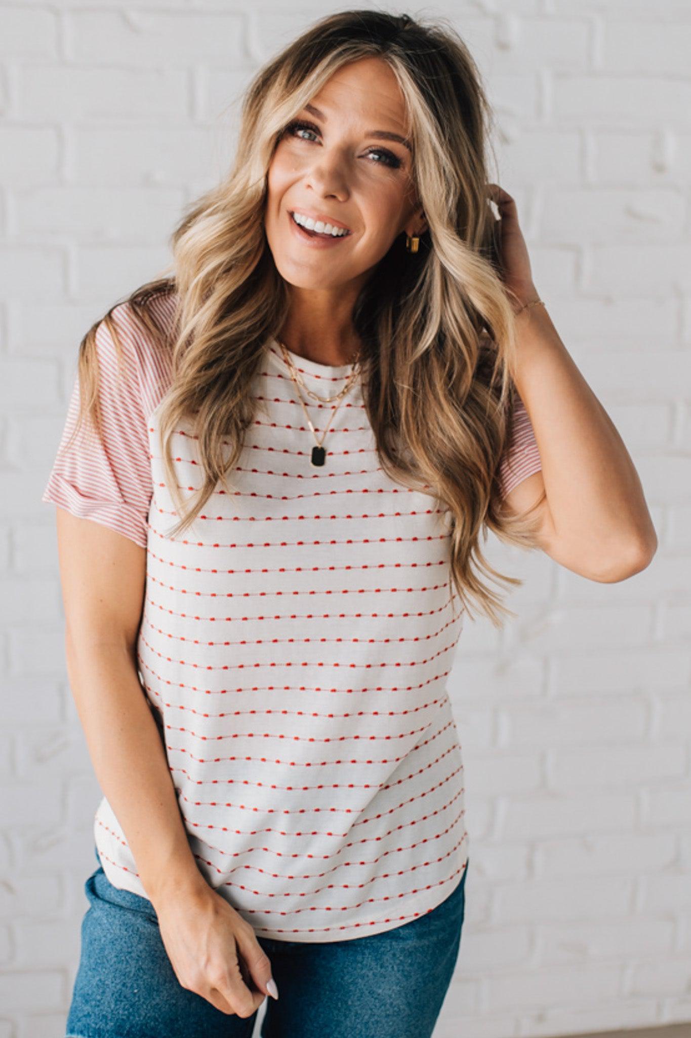 BLONDE WOMAN WEARING A ROUND NECK TOP WITH MICRO STRIPED RAGLAN SHORT SLEEVES, AND DOTTED STRIPE KNIT BODY.