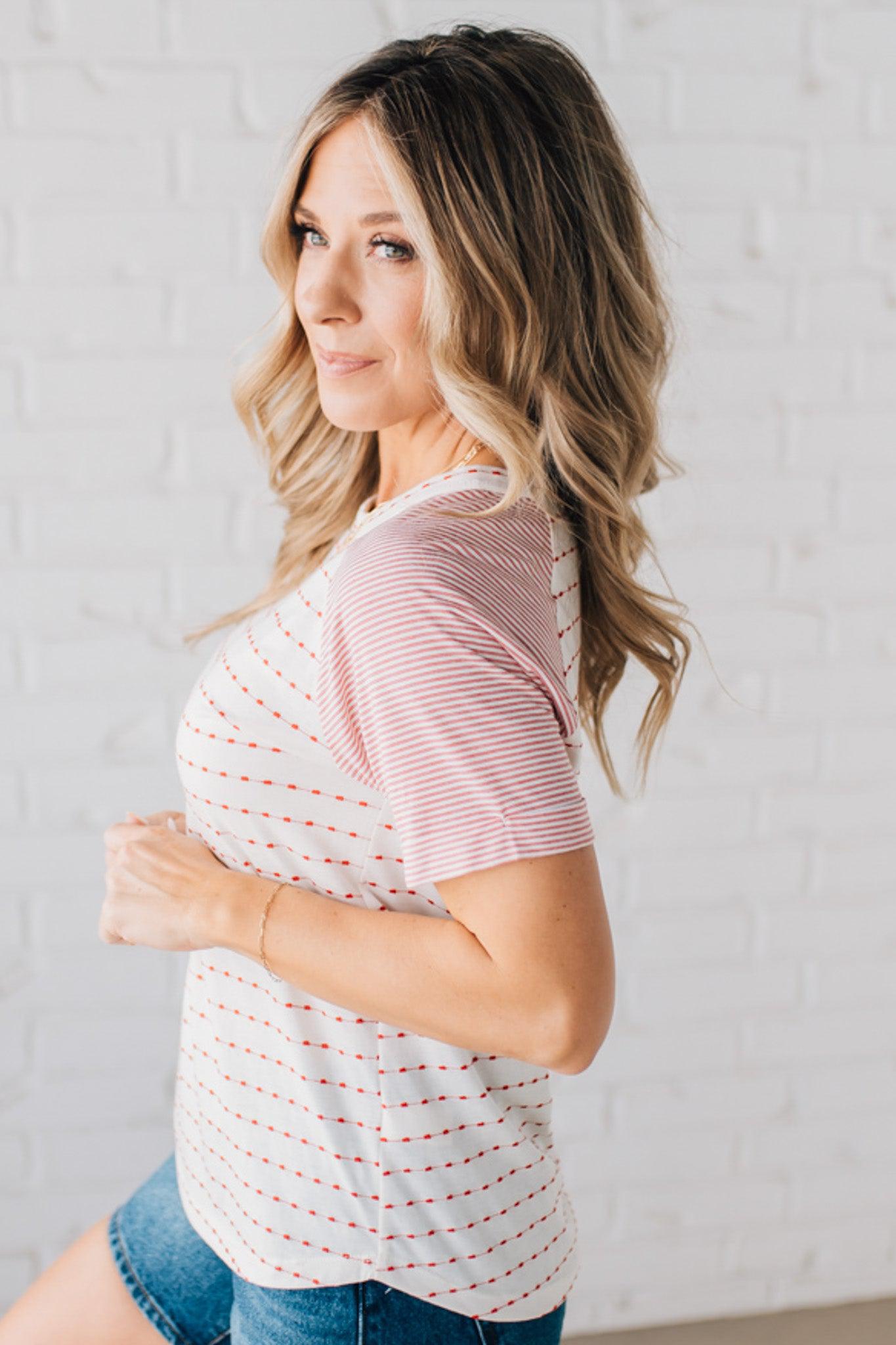 BLONDE WOMAN WEARING A ROUND NECK TOP WITH MICRO STRIPED RAGLAN SHORT SLEEVES, AND DOTTED STRIPE KNIT BODY.