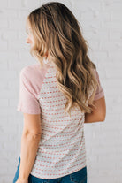 BLONDE WOMAN WEARING A ROUND NECK TOP WITH MICRO STRIPED RAGLAN SHORT SLEEVES, AND DOTTED STRIPE KNIT BODY.