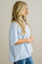 Woman wearing a blue and white striped shirt against a beige wall