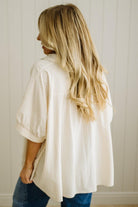Woman wearing a white oversized shirt with a neutral background