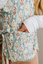 Floral-patterned baby carrier with a person wearing it, blurred background
