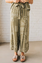 Blonde Woman in Tan Slides Wearing Paisley Print Belted Paper Bag Crop Pants.