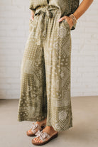 Blonde Woman in Tan Slides Wearing Paisley Print Belted Paper Bag Crop Pants.