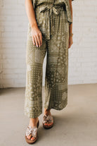 Blonde Woman in Tan Slides Wearing Paisley Print Belted Paper Bag Crop Pants.