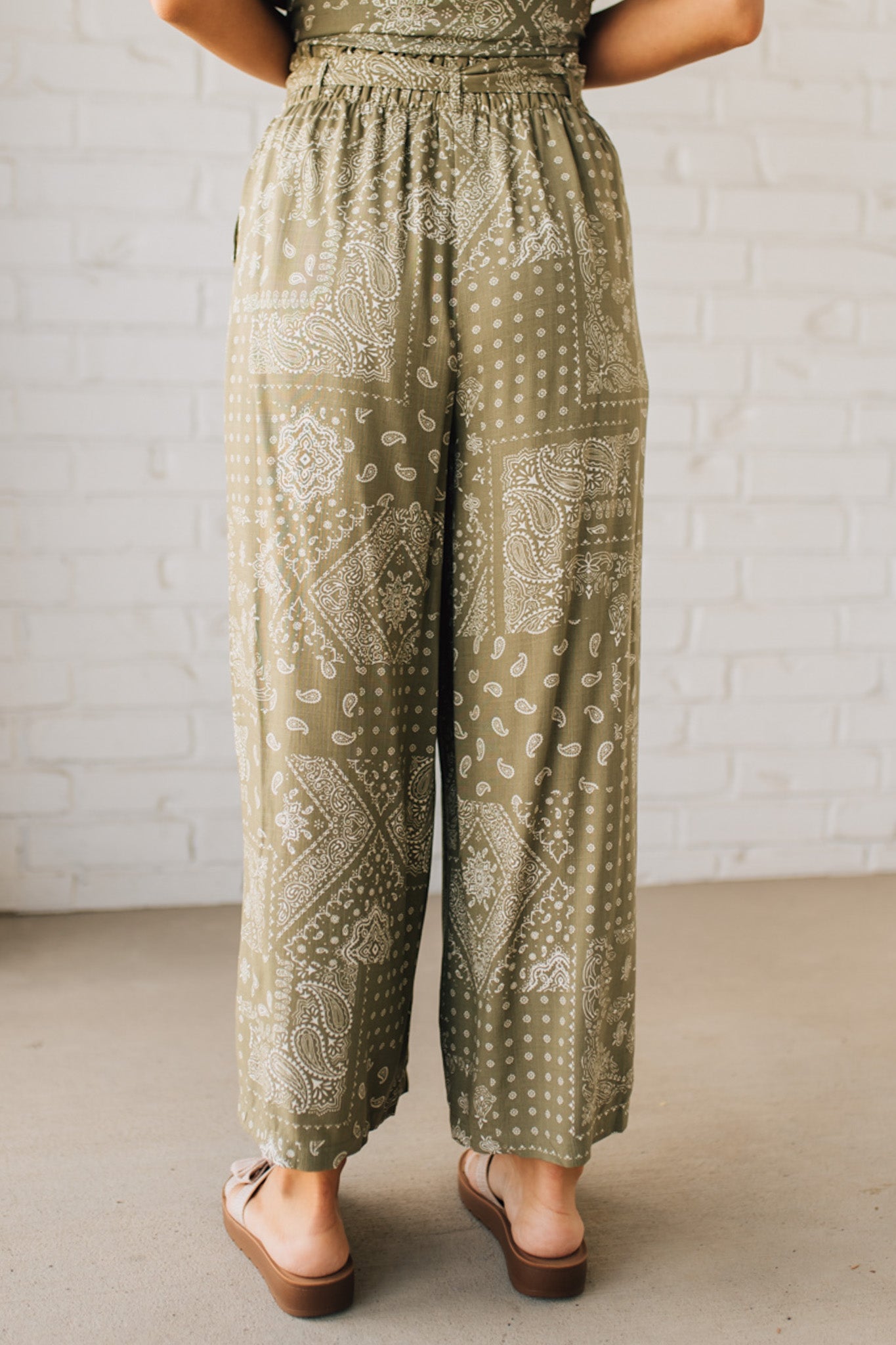 Blonde Woman in Tan Slides Wearing Paisley Print Belted Paper Bag Crop Pants.
