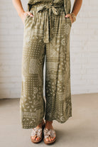 Blonde Woman in Tan Slides Wearing Paisley Print Belted Paper Bag Crop Pants.