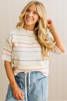 Woman wearing a striped sweater and jeans with a neutral background