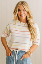 Woman wearing a striped sweater and jeans against a plain background