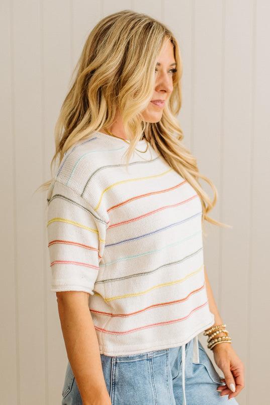 Woman wearing a striped shirt with colorful horizontal lines against a neutral background