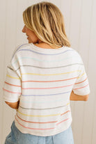 Woman wearing a white t-shirt with colorful horizontal stripes against a plain background