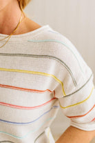 Close-up of a person wearing a white shirt with colorful stripes on a plain background