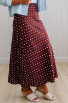 Person wearing a burgundy skirt with white polka dots indoors.