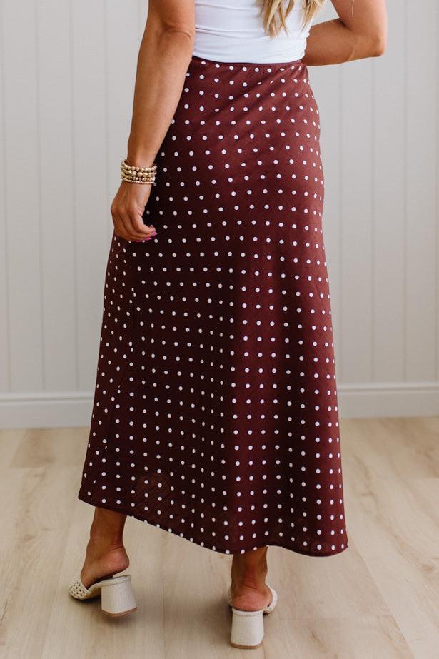 Person wearing a burgundy polka dot skirt with a white background