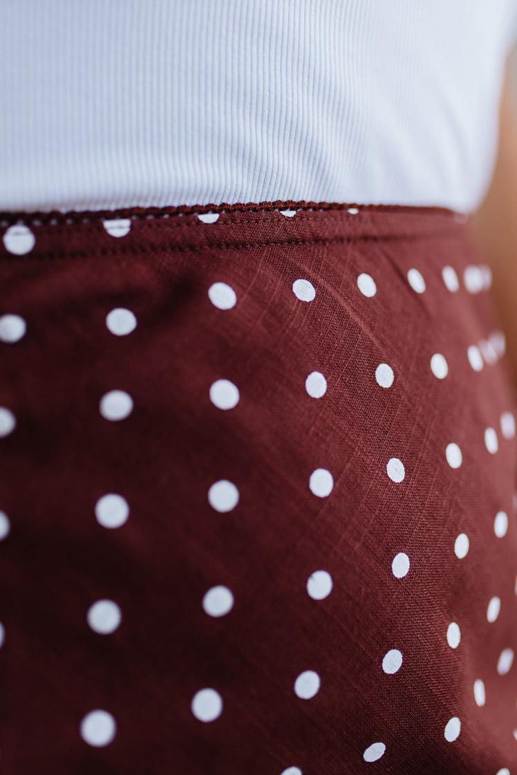 Close-up of a maroon skirt with white polka dots and a white top underneath.