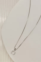 Silver necklace with a horseshoe-shaped pendant on a light gray background