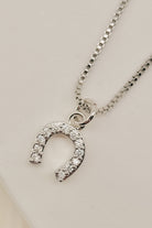 Silver necklace with a horseshoe-shaped pendant on a light gray background