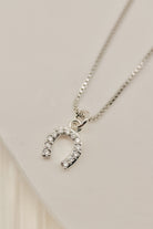 Silver necklace with a horseshoe-shaped pendant on a light gray background